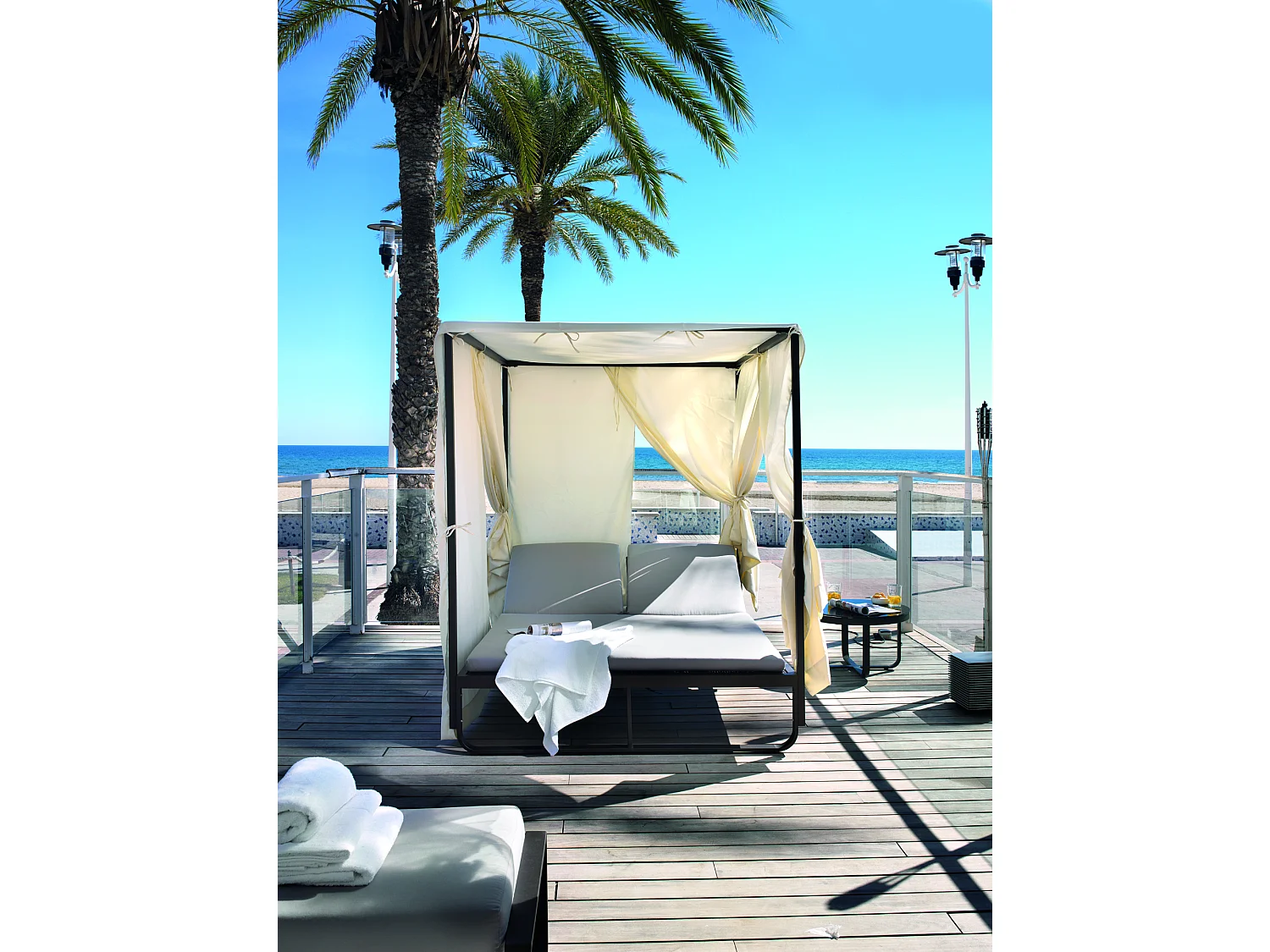 Chaise longue double marron avec rideaux couleur écru et coussin couleur lin