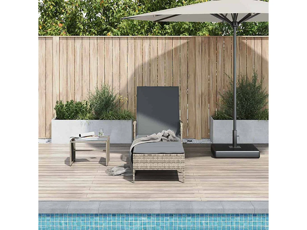 Chaise longue avec coussin gris en poly rattan.