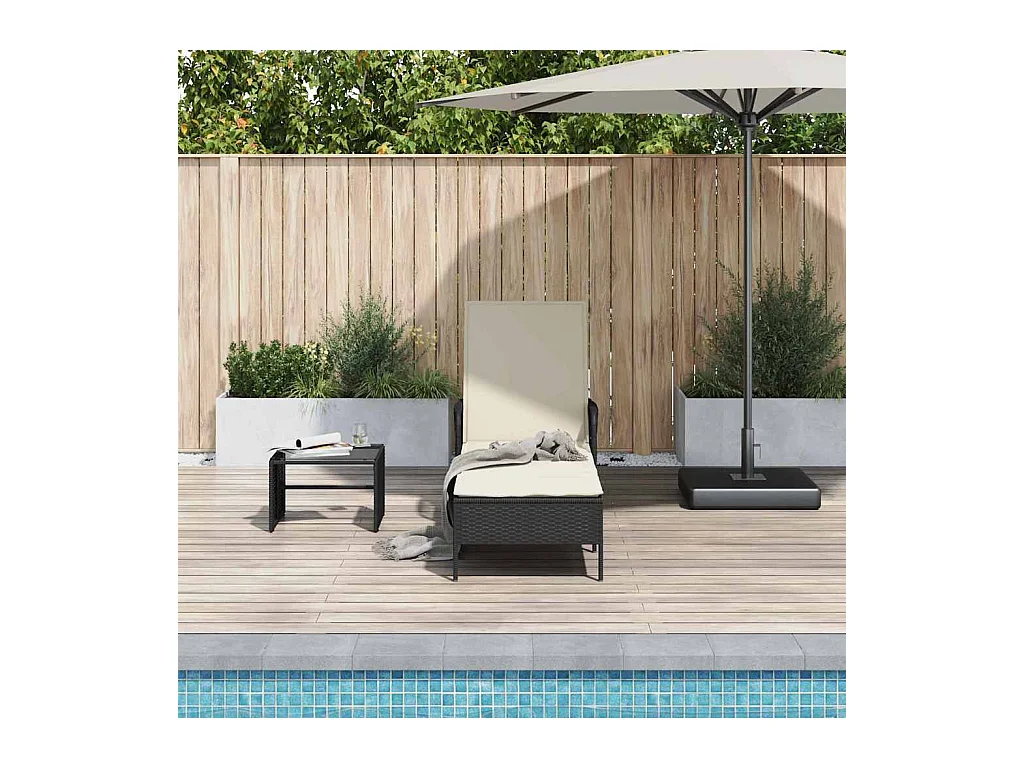 Tumbona con cojín de ratán sintético negro.