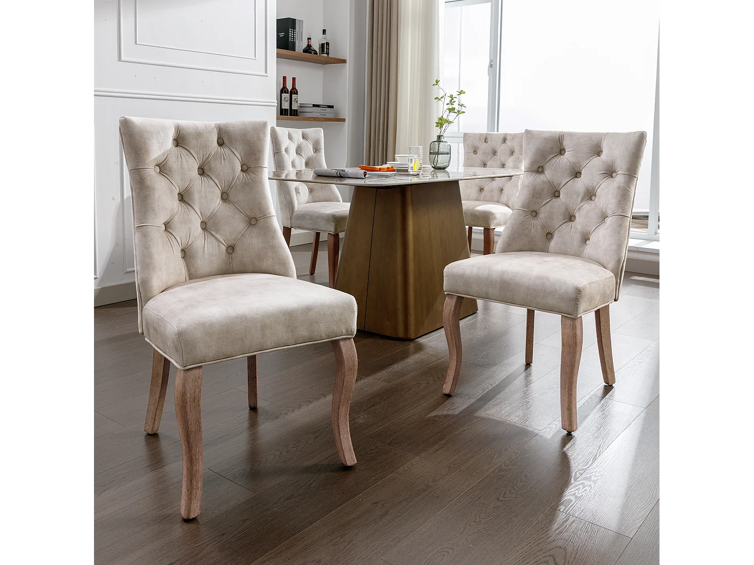 Conjunto de 4 sillas de terciopelo beige claro con patas de madera curvadas y botones decorativos.