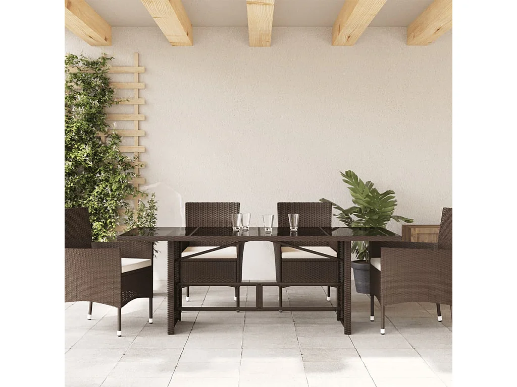 Mesa de jardín con tapa de cristal marrón y resina trenzada.