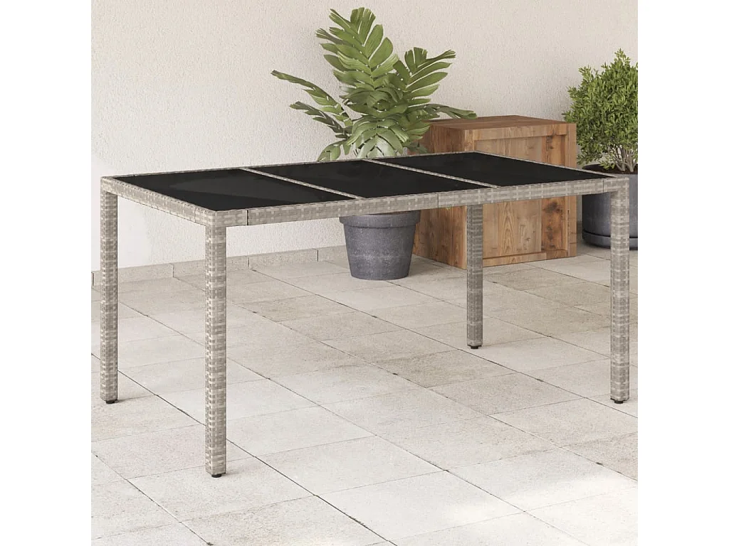 Mesa de jardín con tablero de cristal gris claro y resina trenzada.