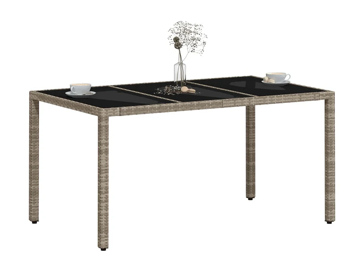 Mesa de jardín con tablero de cristal gris claro y resina trenzada.