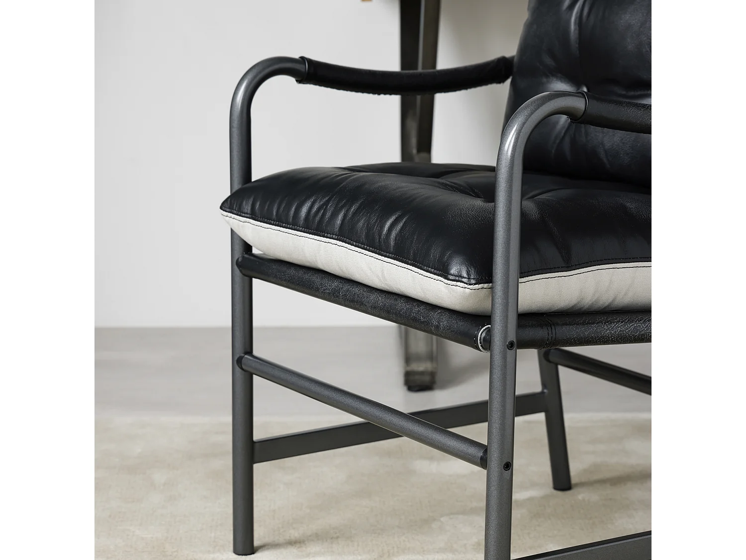Sillón moderno de cuero negro con estructura metálica