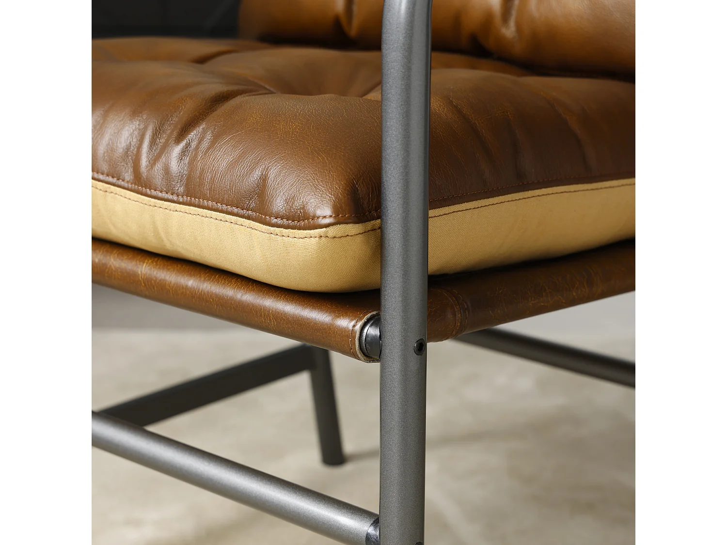 Sillón moderno de cuero marrón con estructura metálica